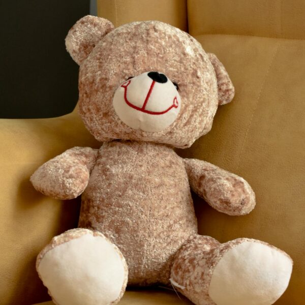 photo by abdulvahap demir Adorable brown teddy bear resting on a yellow chair, perfect for children's room decor.