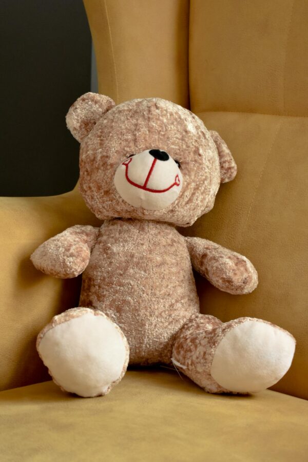Adorable brown teddy bear resting on a yellow chair, perfect for children's room decor.